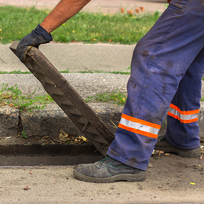 worker lifting a drainage grate